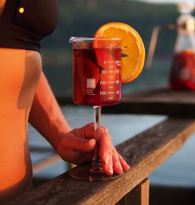 A person holding the beaker cup filled with wine