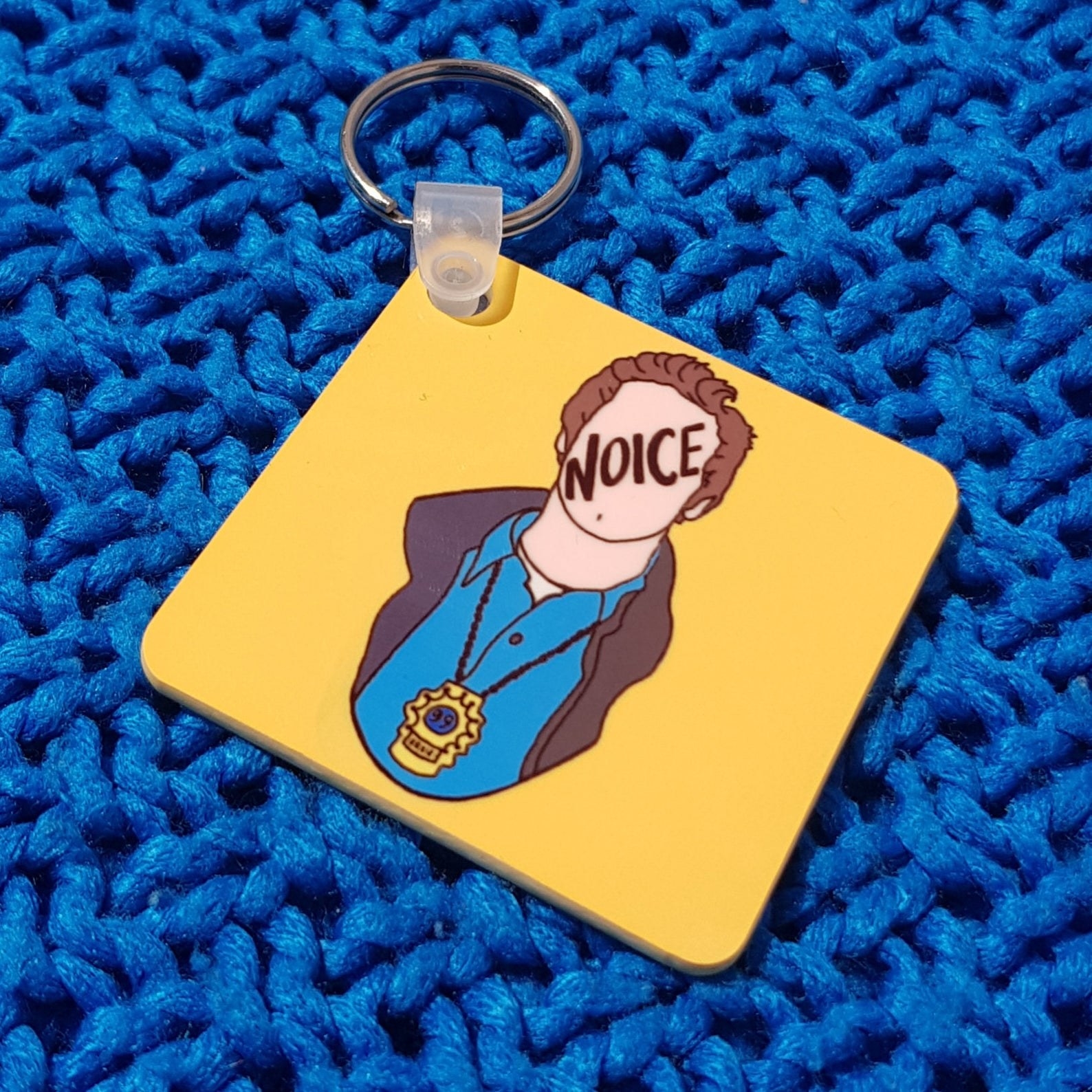 A minimalist drawing of Jake with the word &quot;noice&quot; over his face, on a yellow background and attached to a key ring