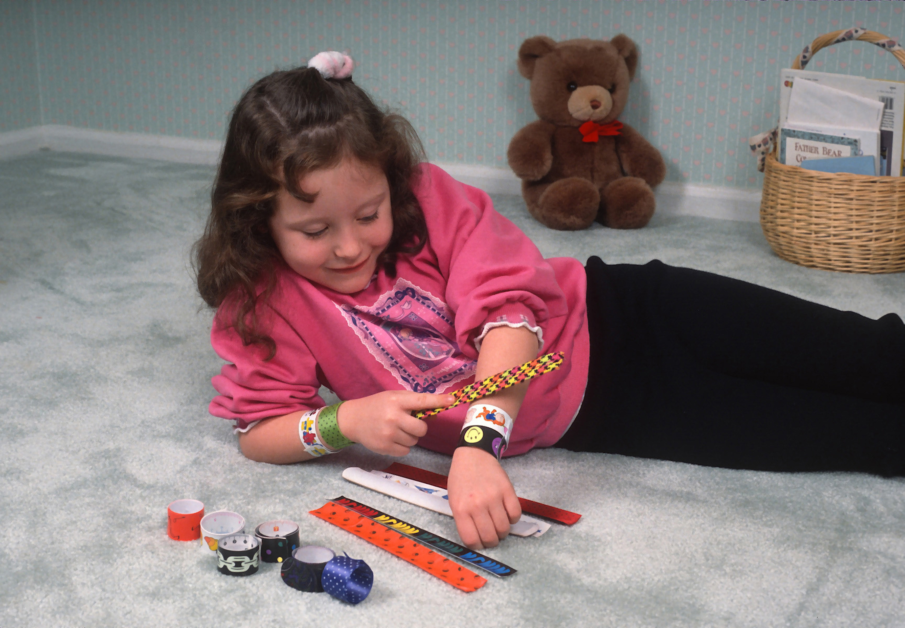 A young girl showing her snap bracelets on her wrist, with more on the floor