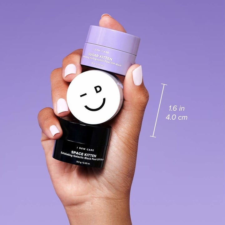 hand holding the purple, white, and black mini masks 