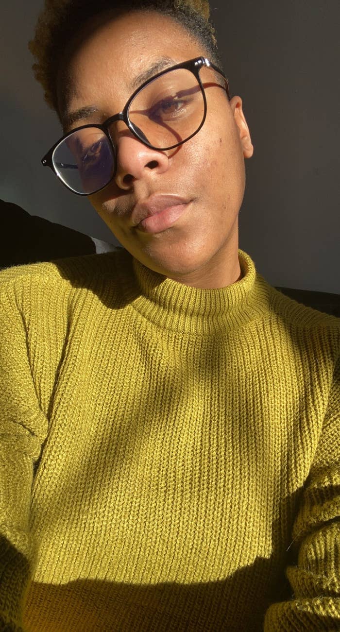 An African-American woman with short hair and glasses is looking at the camera as the light from the sun hits her face. 