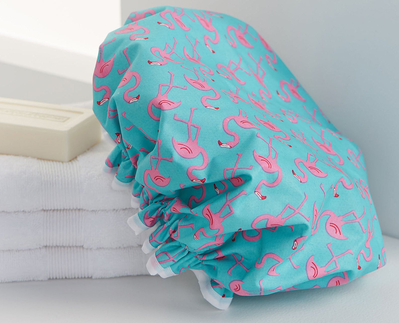 A bright shower cap with flamingos printed all over it