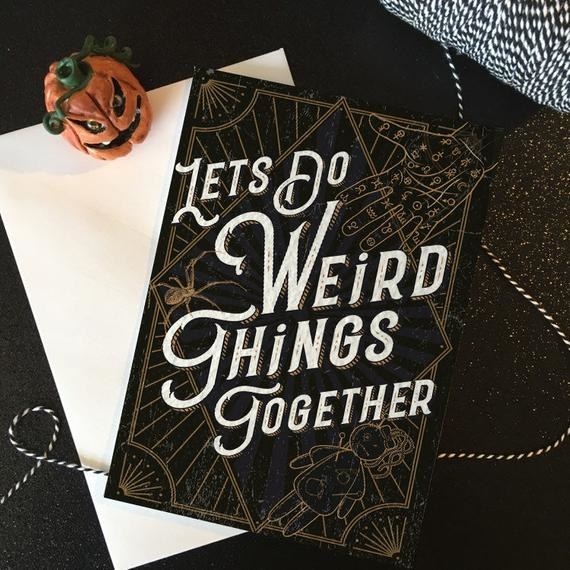 A black card with gold etchings of a voodoo doll and a palmistry hand, and the words "Let's do weird things together" in white