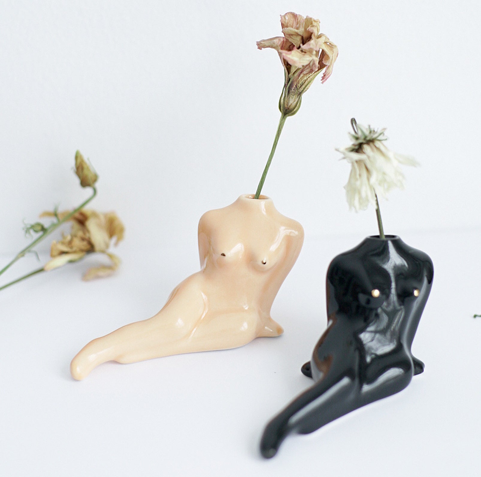 Two body-shaped flower vases with flowers sticking out of them 