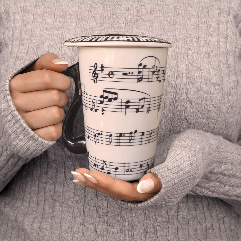 A person holding a mug with a music staff on the side