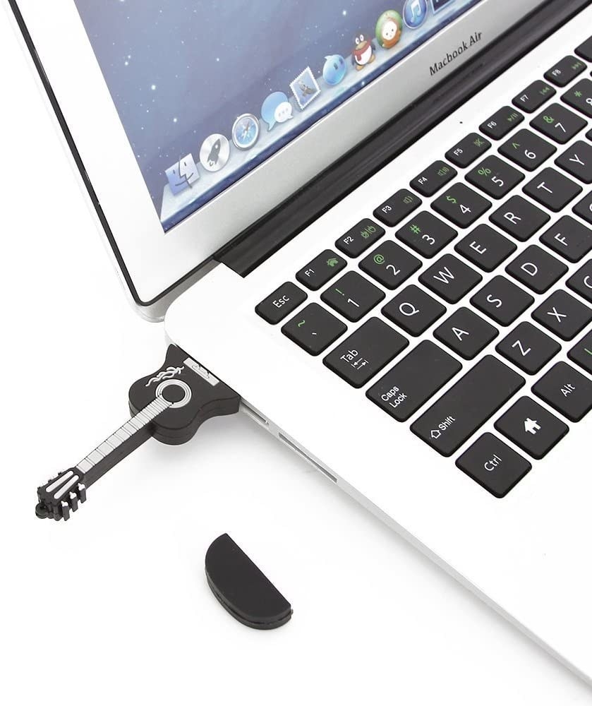 A flash drive in the shape of a guitar plugged into the side of a laptop