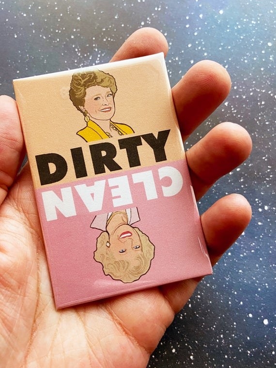 A hand holding the beige and pink magnet which has Blanche on the dirty side and Rose on the clean side