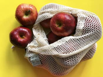 A large reusable produce bag filled with apples