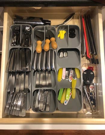 A reviewer photo of an open drawer filled with three drawer organizers sitting side-by-side and filled with an array of different utensils