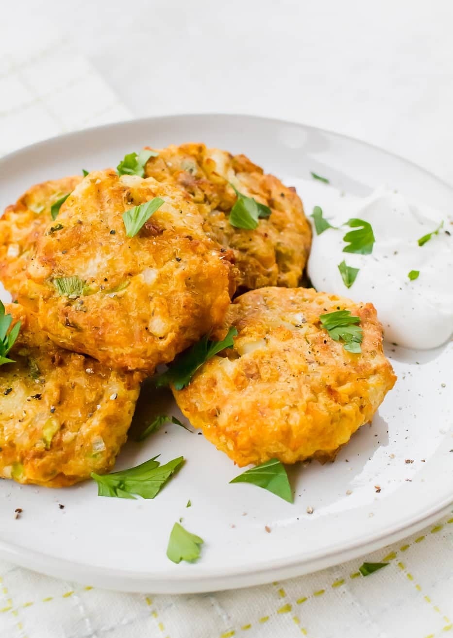 A plate of air fried potato pancakes with sour cream on the side.