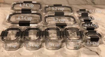 A reviewer photo of the 24-piece set laid out with all of the storage amounts labeled including two that hold 4.7 cups, two that hold 3.2 cups, four that hold 1.3 cups, and four that hold 0.5 cups 