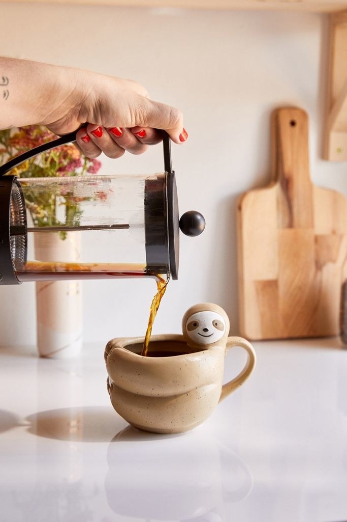 coffee being poured into the sloth-shaped mug