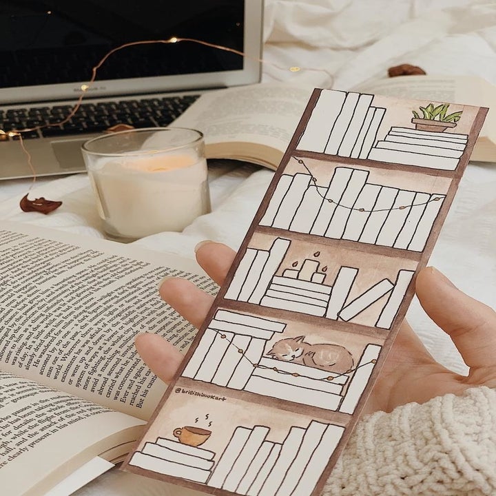 a hand holding the bookmark with blank spaces on it shaped like books