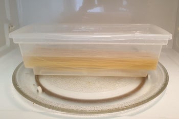 A reviewer photo of uncooked pasta and water in the clear, plastic microwave pasta cooker 