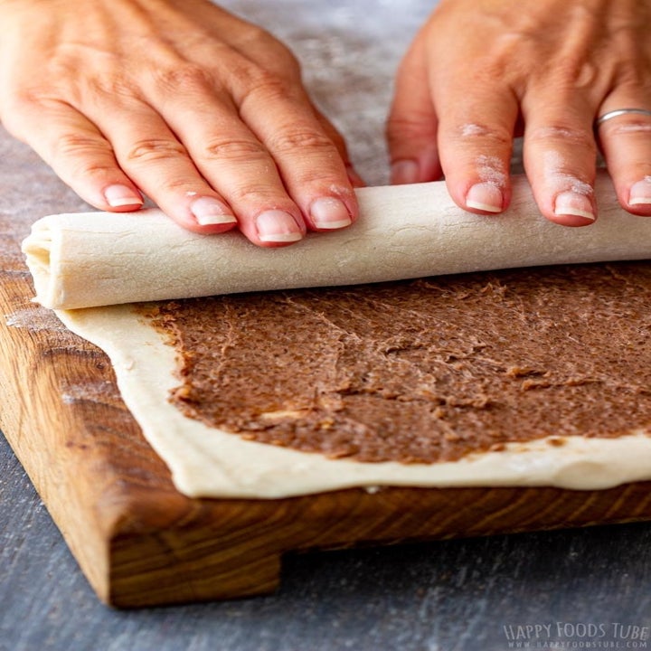 Rolling up dough with cinnamon sugar filling.