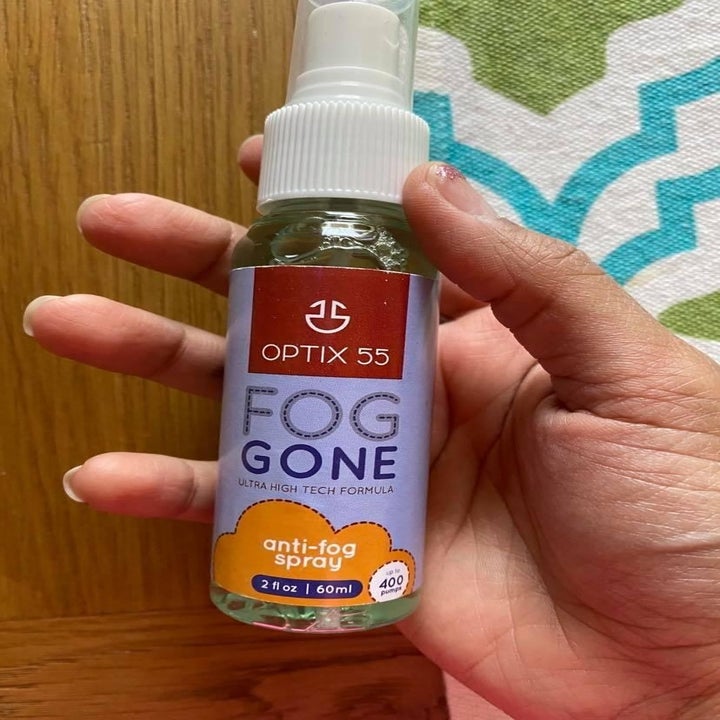 A different reviewer holding the bottle of anti-fog spray