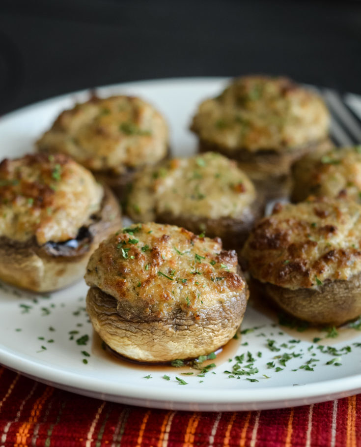 A plate of stuffed cheesy mushrooms with herbs.