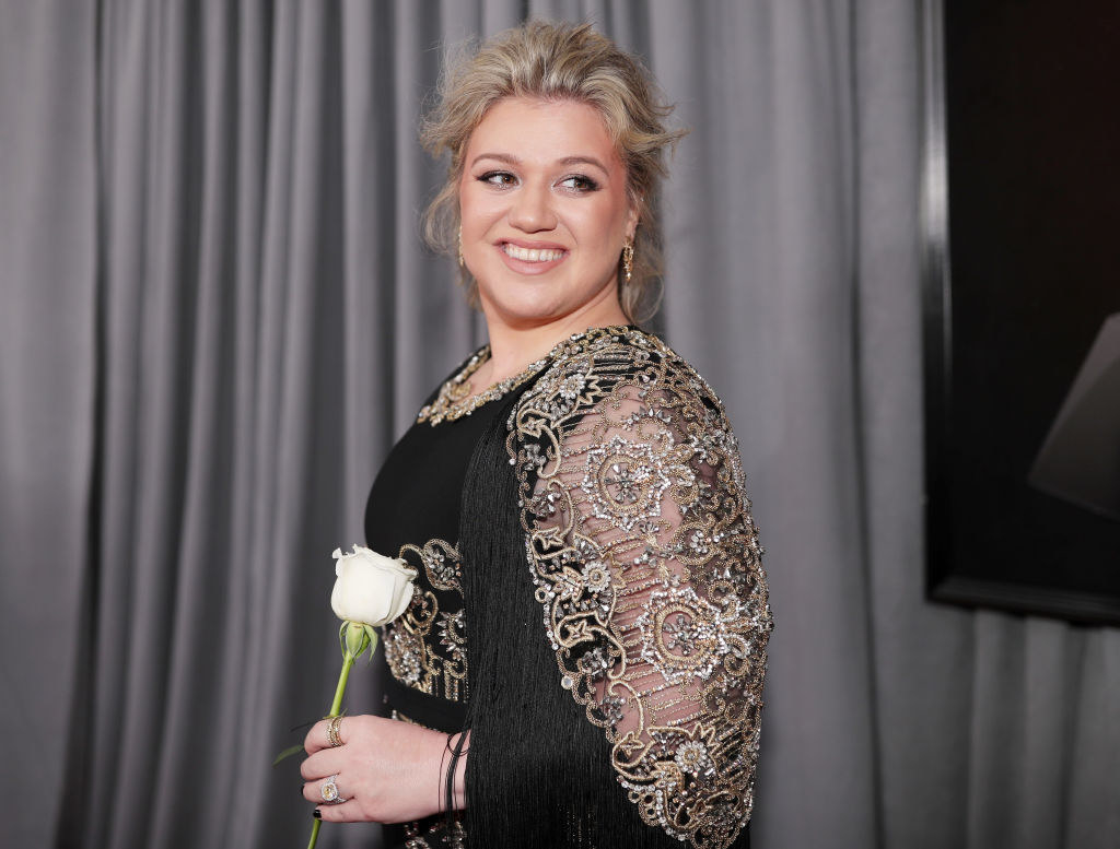 Kelly smiling and holding a rose