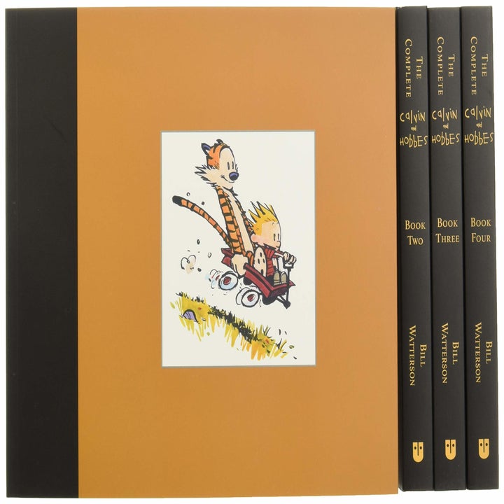 four volumes of hardcover books with calvin and hobbes sledding on the front 