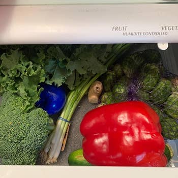 The Bluapple in a fridge drawer filled with fresh produce 
