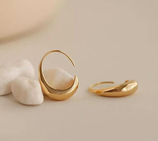 A pair of oval-shaped gold earrings on a plain background