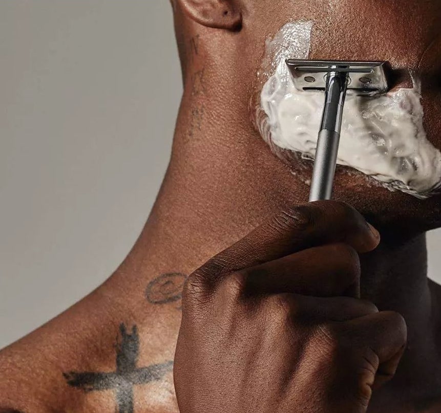A model using the shaving cream and razor on their face