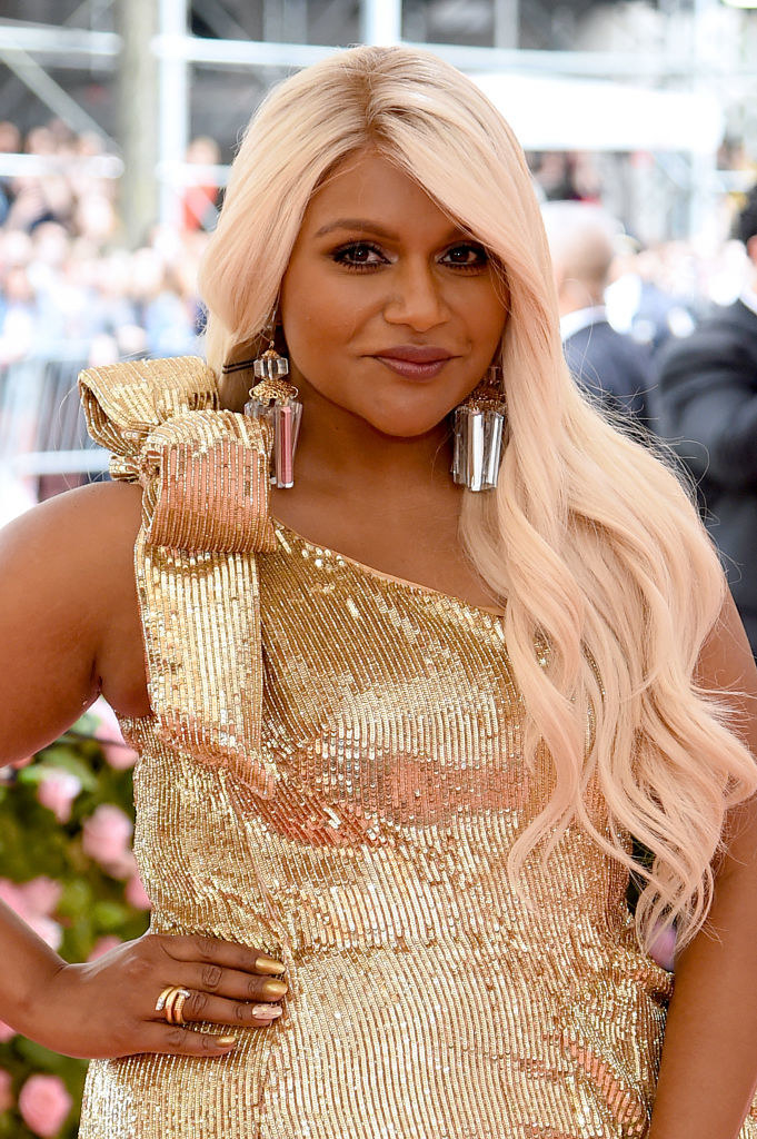 Mindy grinning in a metallic dress and wig