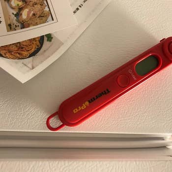 A reviewer photo of the red meat thermometer sticking to the refrigerator 