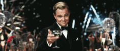 Leonardo DiCaprio raises a glass of champagne as fireworks go off behind him. 