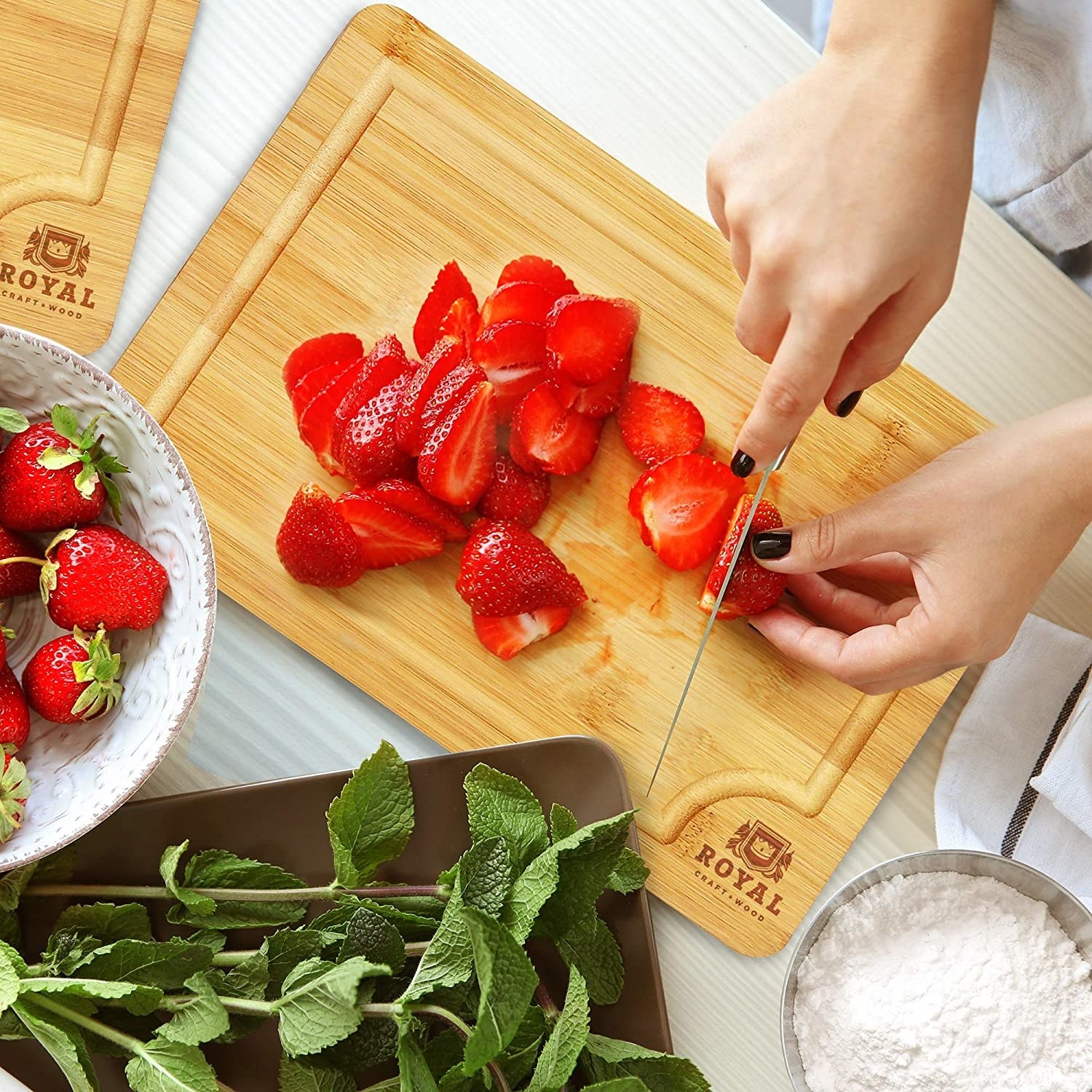 Model uses the bamboo cutting board to cut strawberries