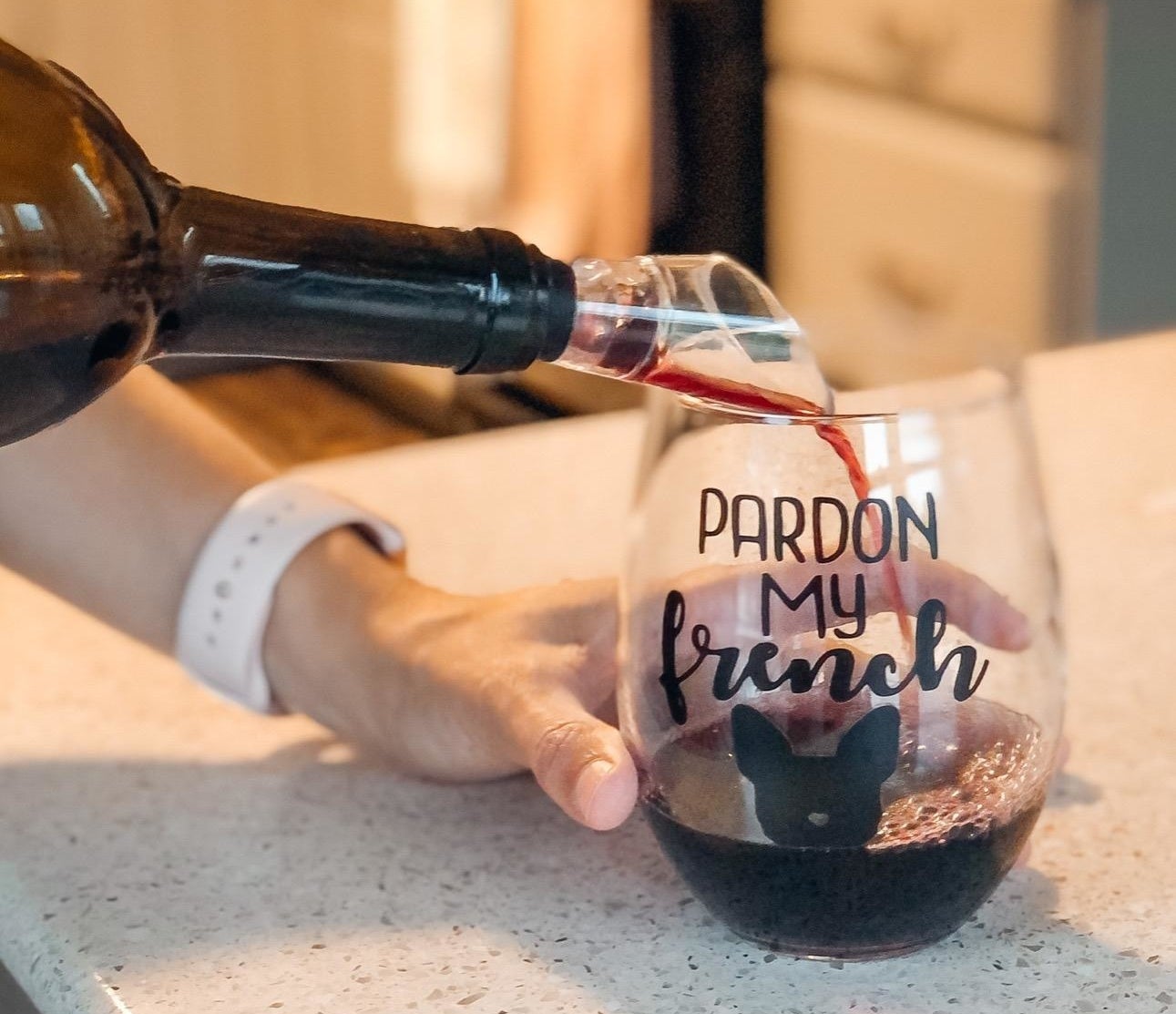 A reviewer photo of a hand pouring a bottle of wine with an aerator stuck in the top into a wine glass that says &quot;Pardon my french&quot; with an image of a French Bulldog head 