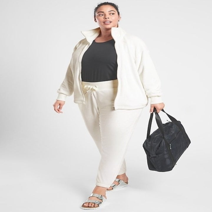 A model wearing the jogger set and holding a bag