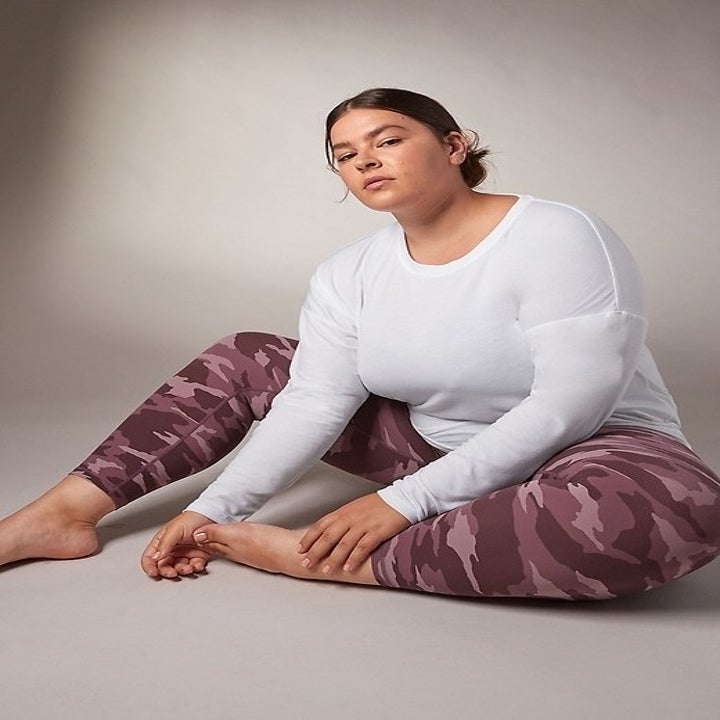 A model sitting wearing the camo yoga pants in mauve