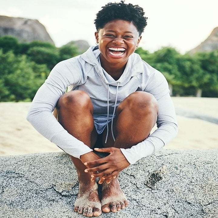 A model laughing while wearing the sweatshirt in light grey