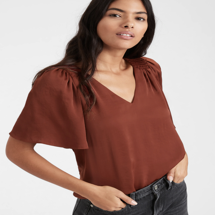 Model wearing satin flutter-sleeve top in the shade burnt caramel brown