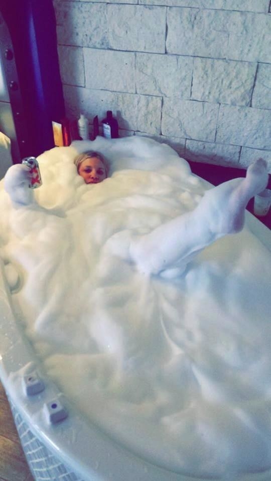 a woman covered from neck to toe in bubbles soaking in a deep bath