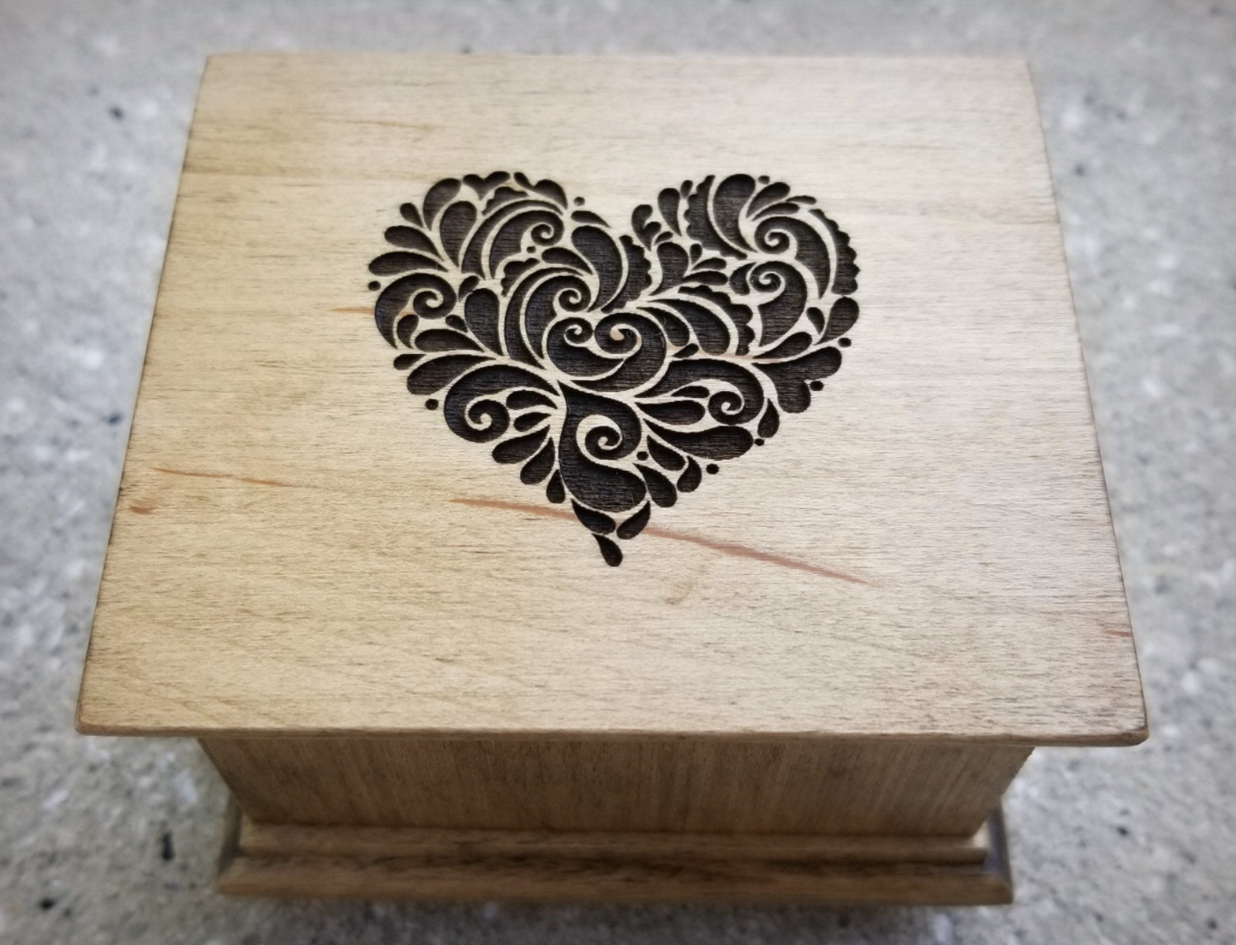 the wooden music box with a carving of a heart on it