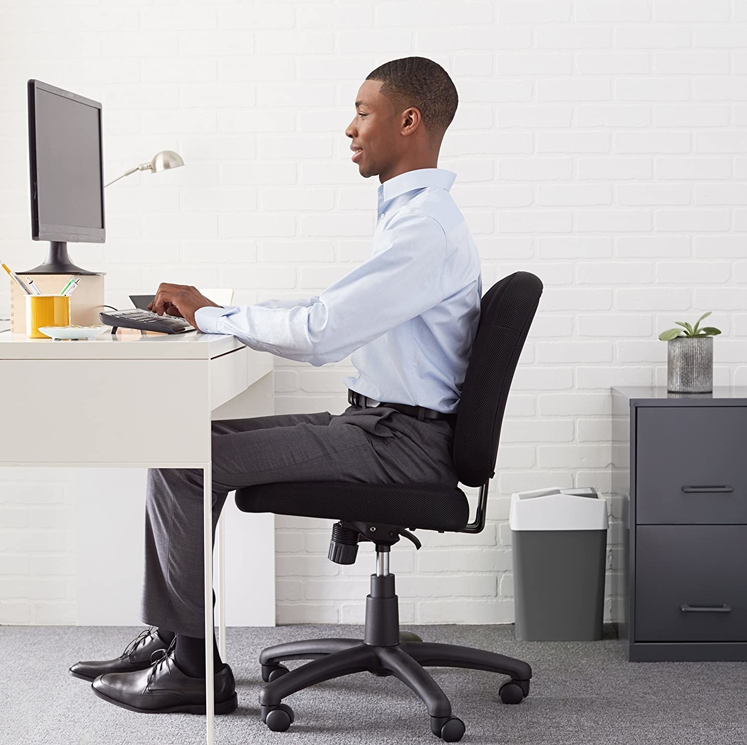 A person sitting at their desk on a chair with wheels