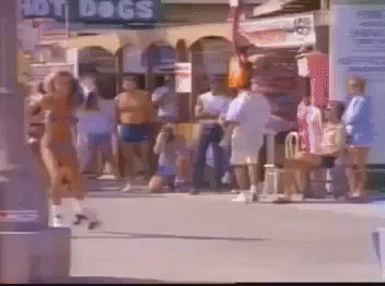 Women in bikinis roller skate down a beach boardwalk holding boomboxes in the &#x27;80s