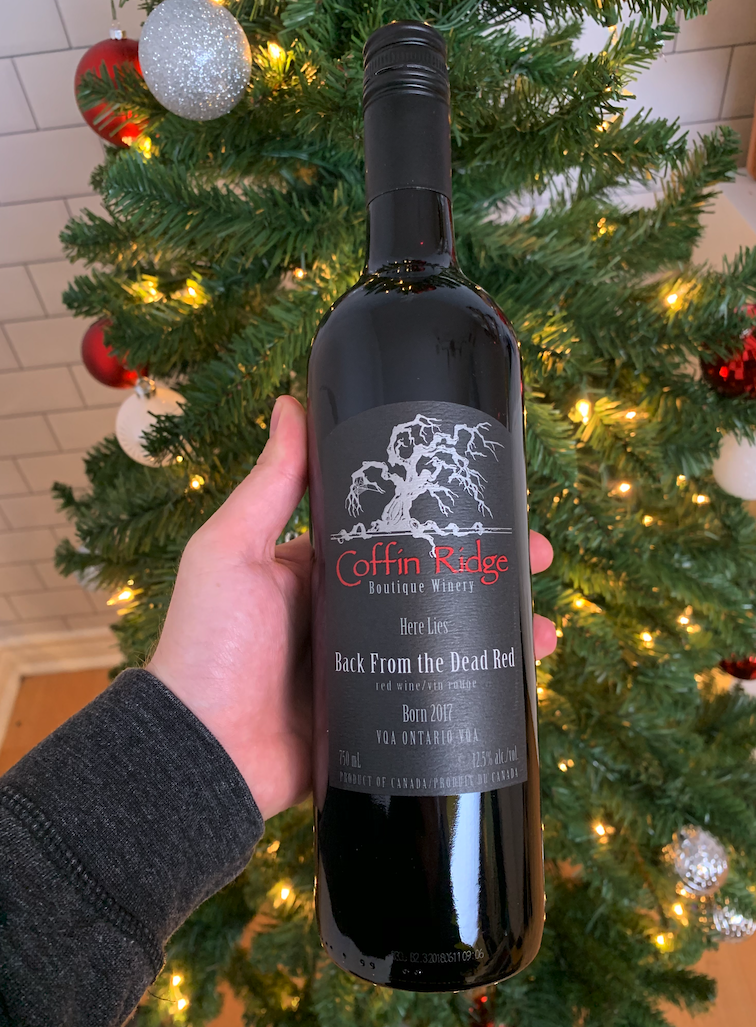A bottle of Coffin Ridge red wine in front of a Christmas Tree.
