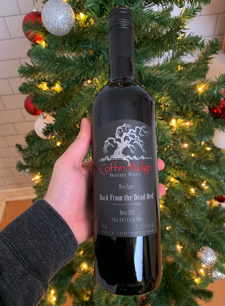 A bottle of  Coffin Ridge red wine in front of a Christmas Tree.