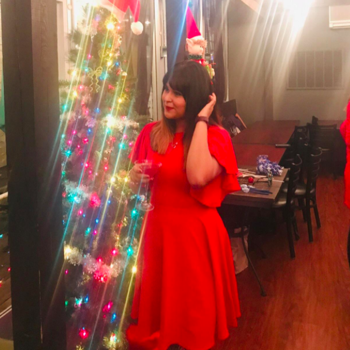 A customer review photo of them wearing the dress next to a Christmas tree