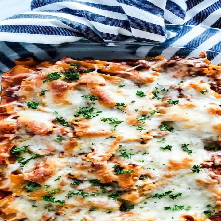 A baking dish filled with baked pasta topped with melted cheese and herbs.