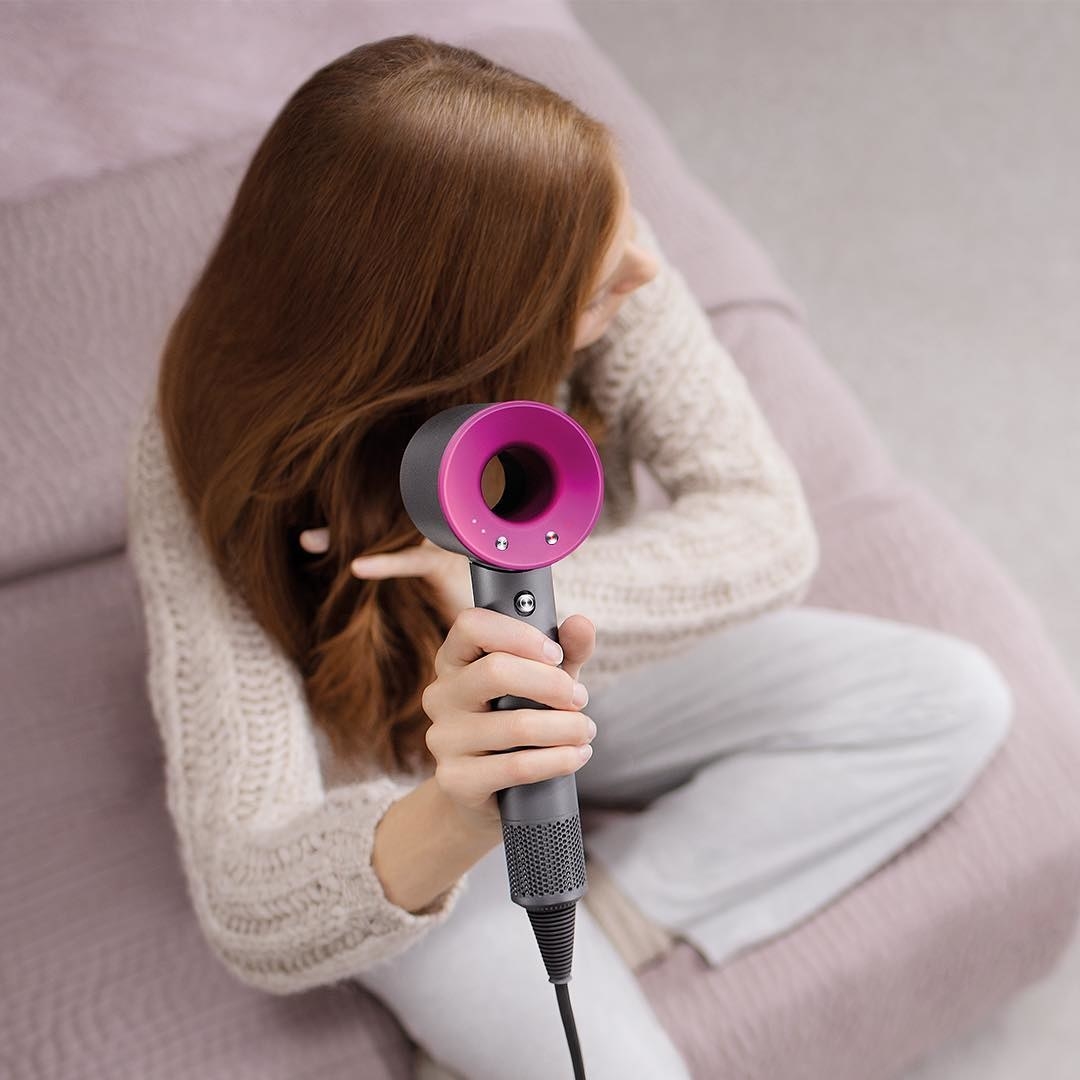 A person using the hair dryer to dry their hair