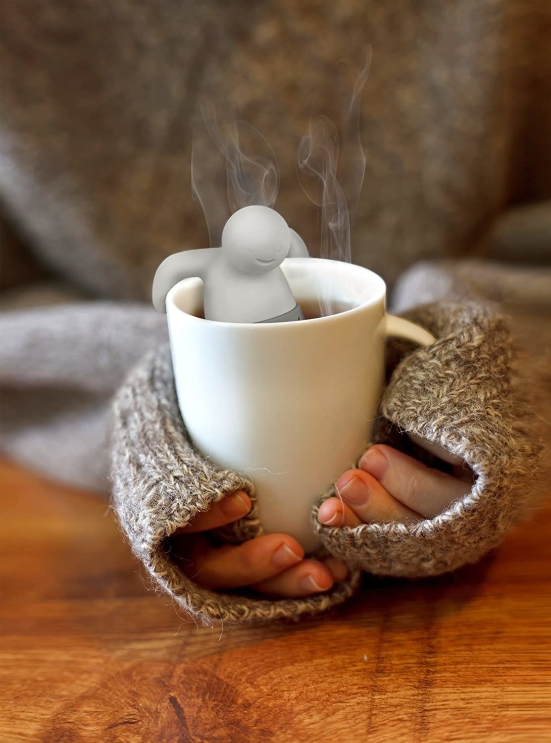person holding mug with tea infuser in it