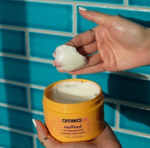 A person scooping out some of the Amika hair mask, showing that the texture is very thick