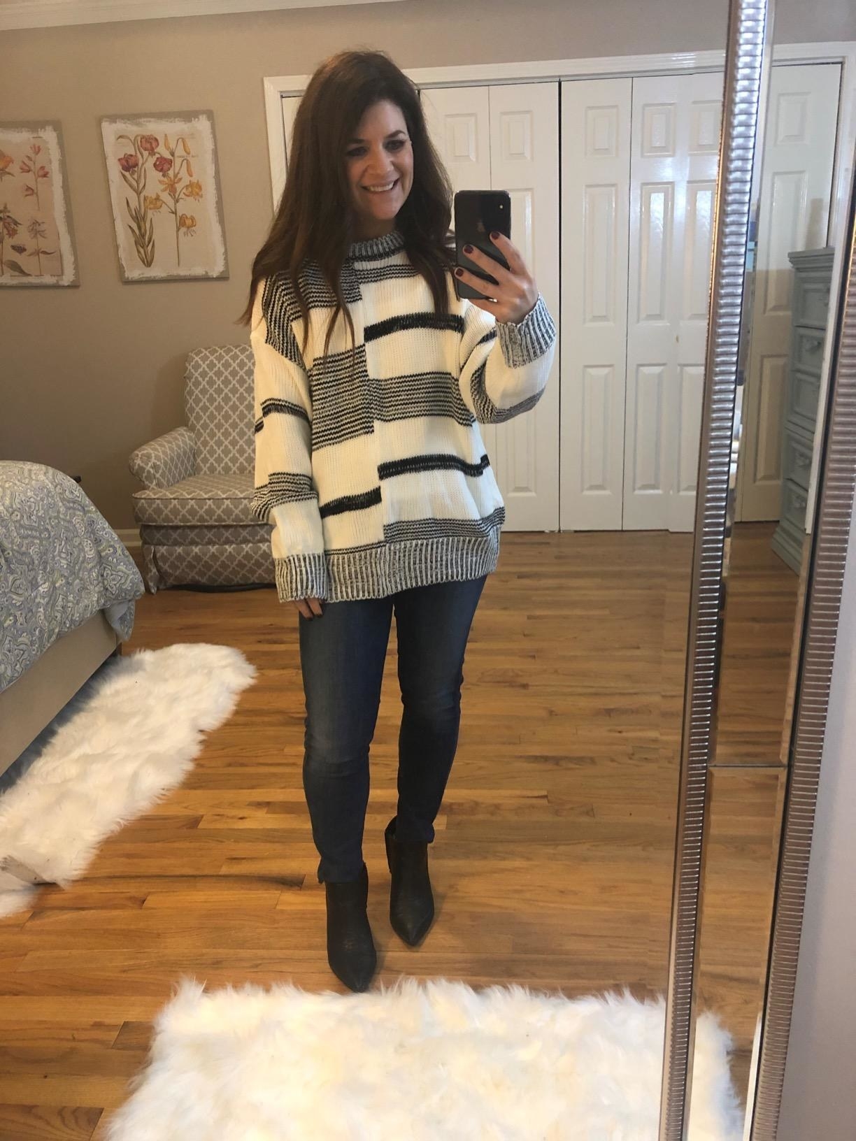 Reviewer wearing the  sweater with black and white stripes that are off-center and meet in the middle