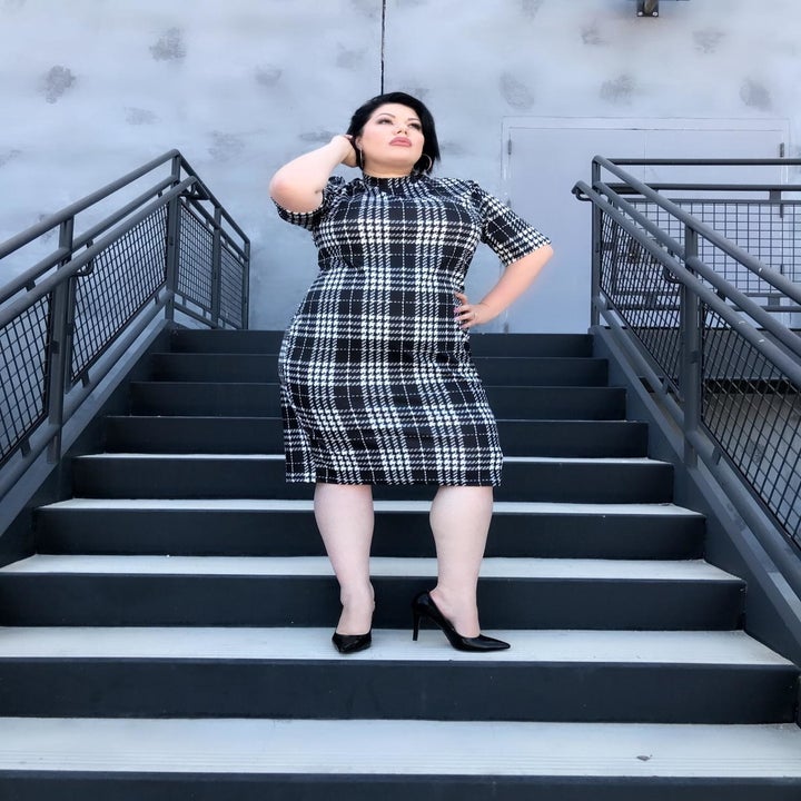 A different reviewer wearing the dress in a black and grey plaid 