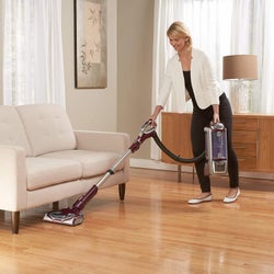 Model using the detachable part of the vacuum to clean under furniture