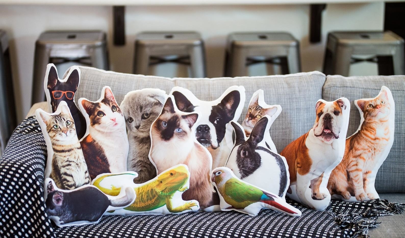 A collection of pillows that look like various pets (cats dogs, birds, etc.)